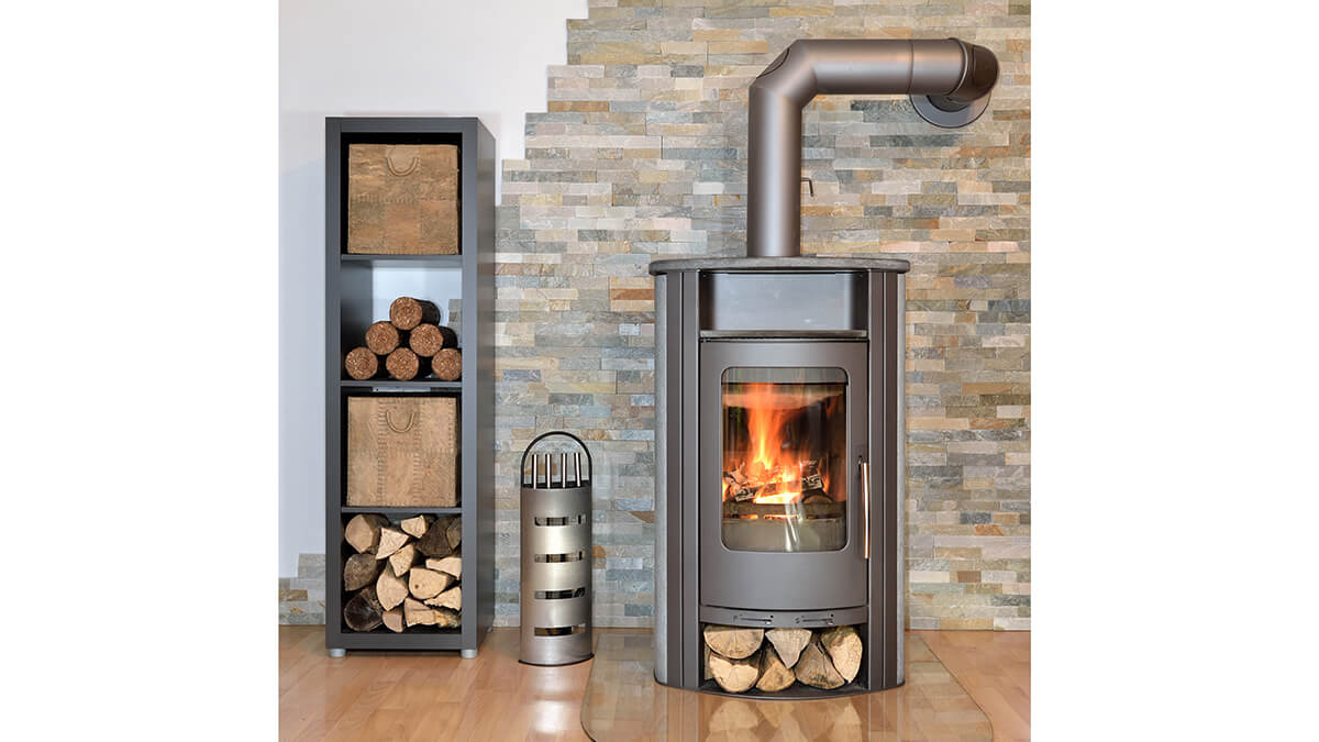 lit household wood burning stove with wood store to side