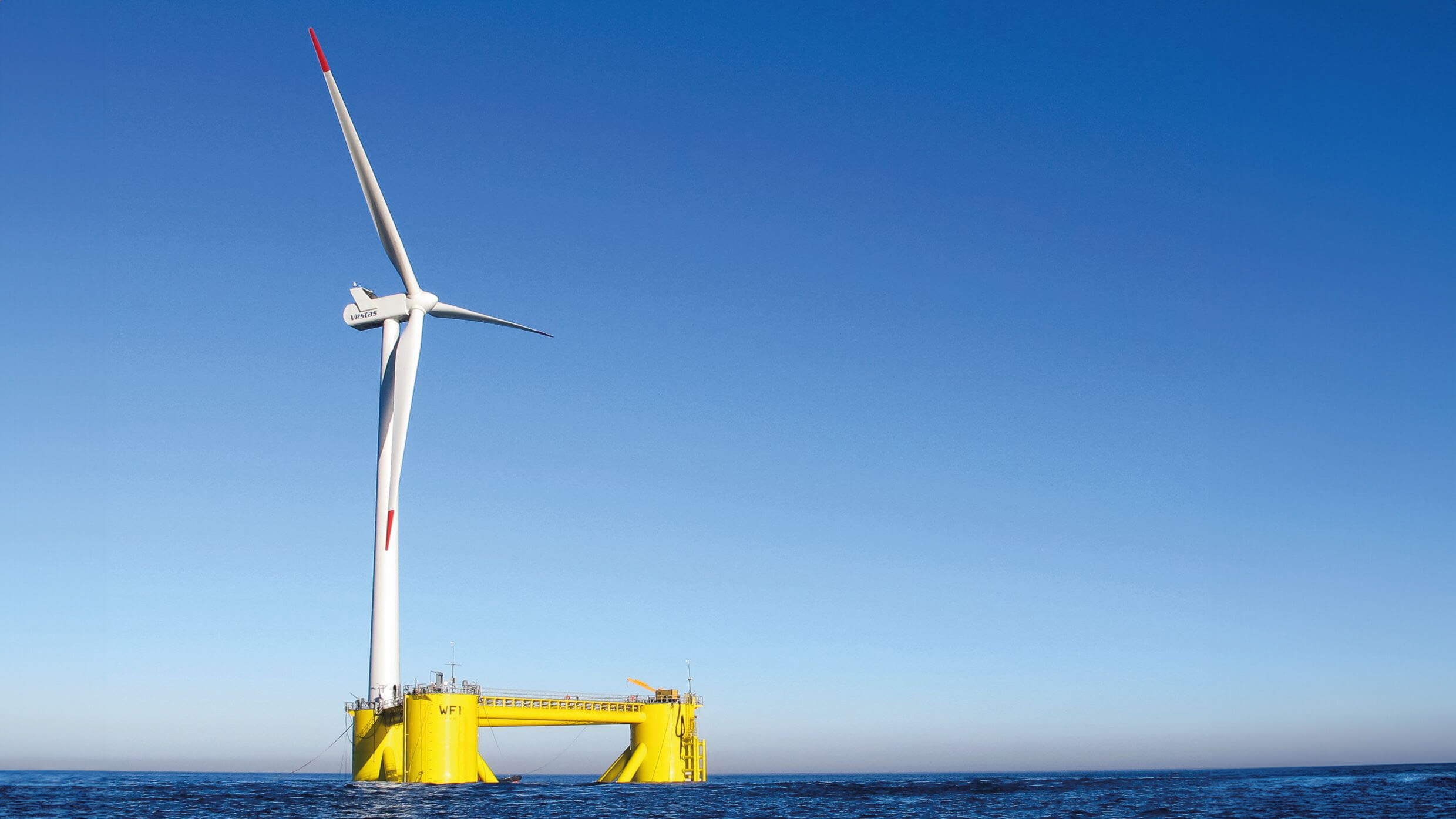 single offshore floating wind turbine in calm sea set against blue sky