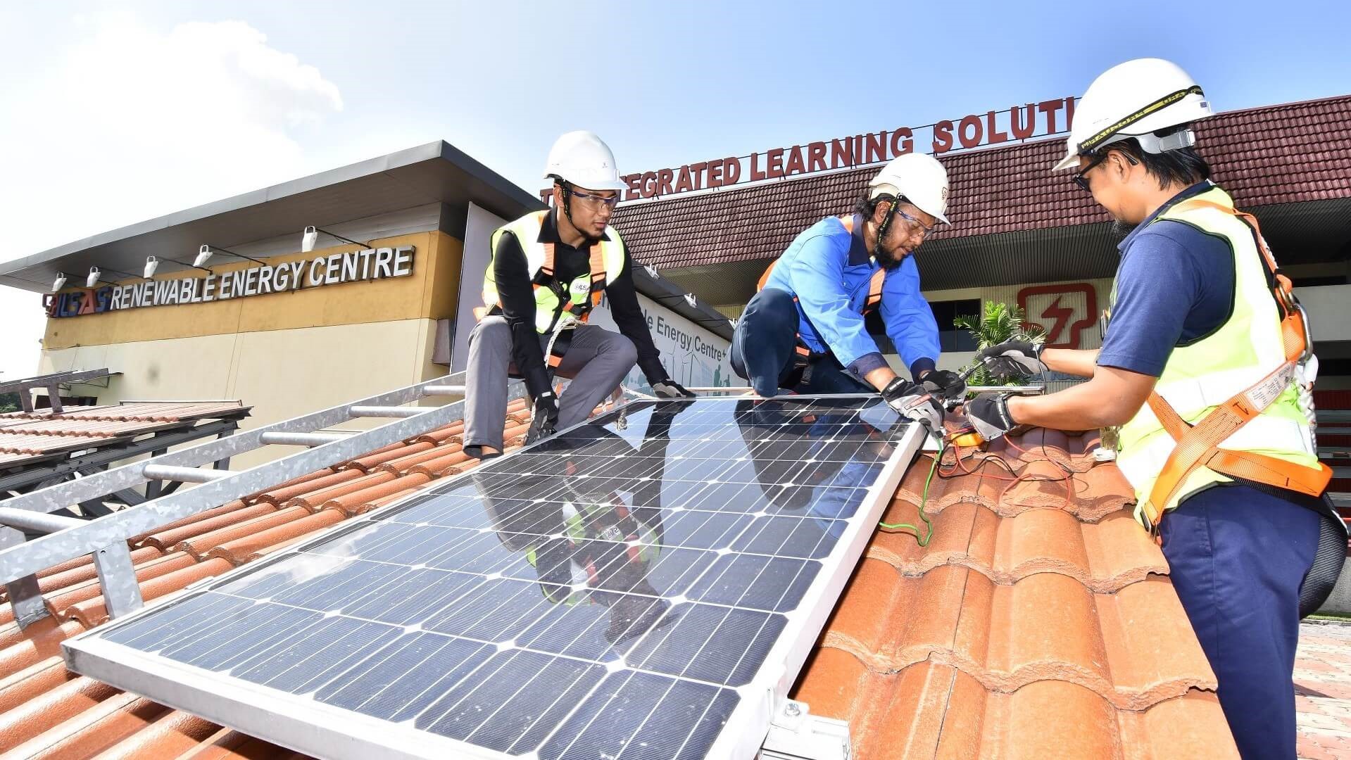 three people installing solar panel on roof
