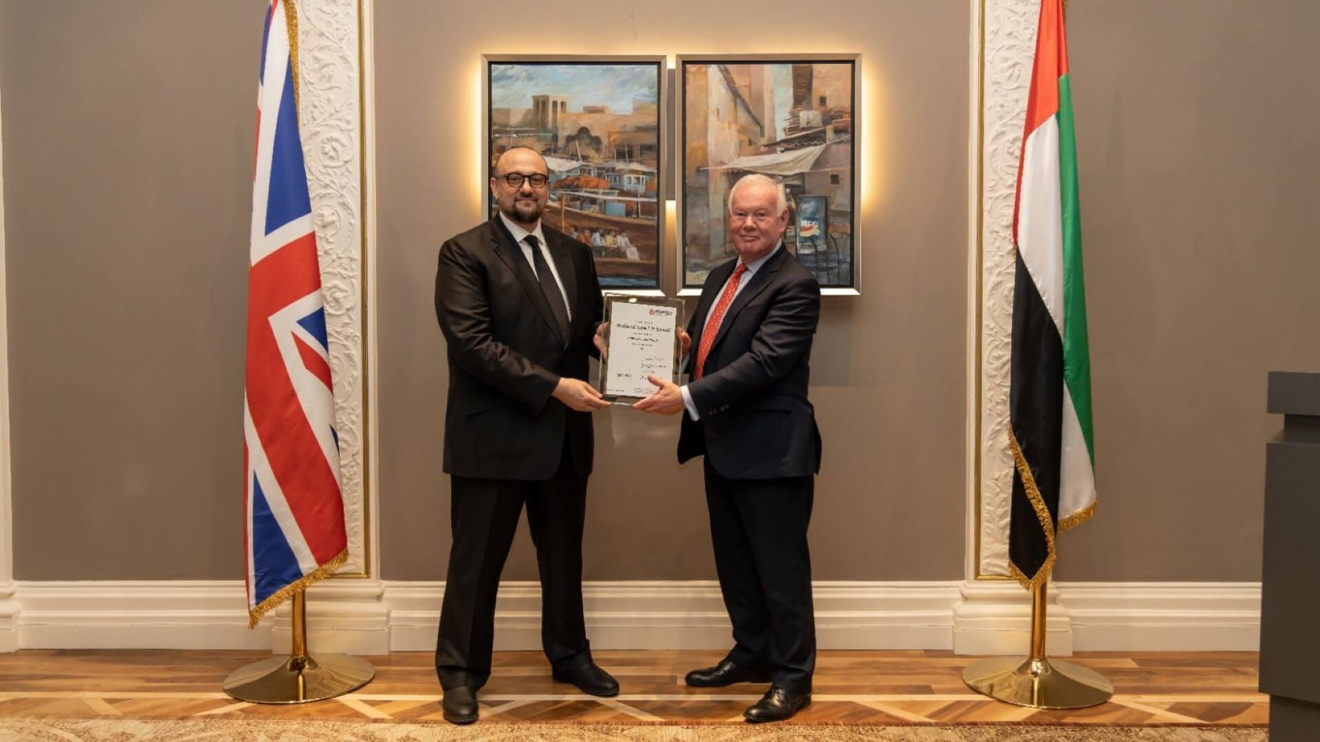 two men holding award in front of national flags