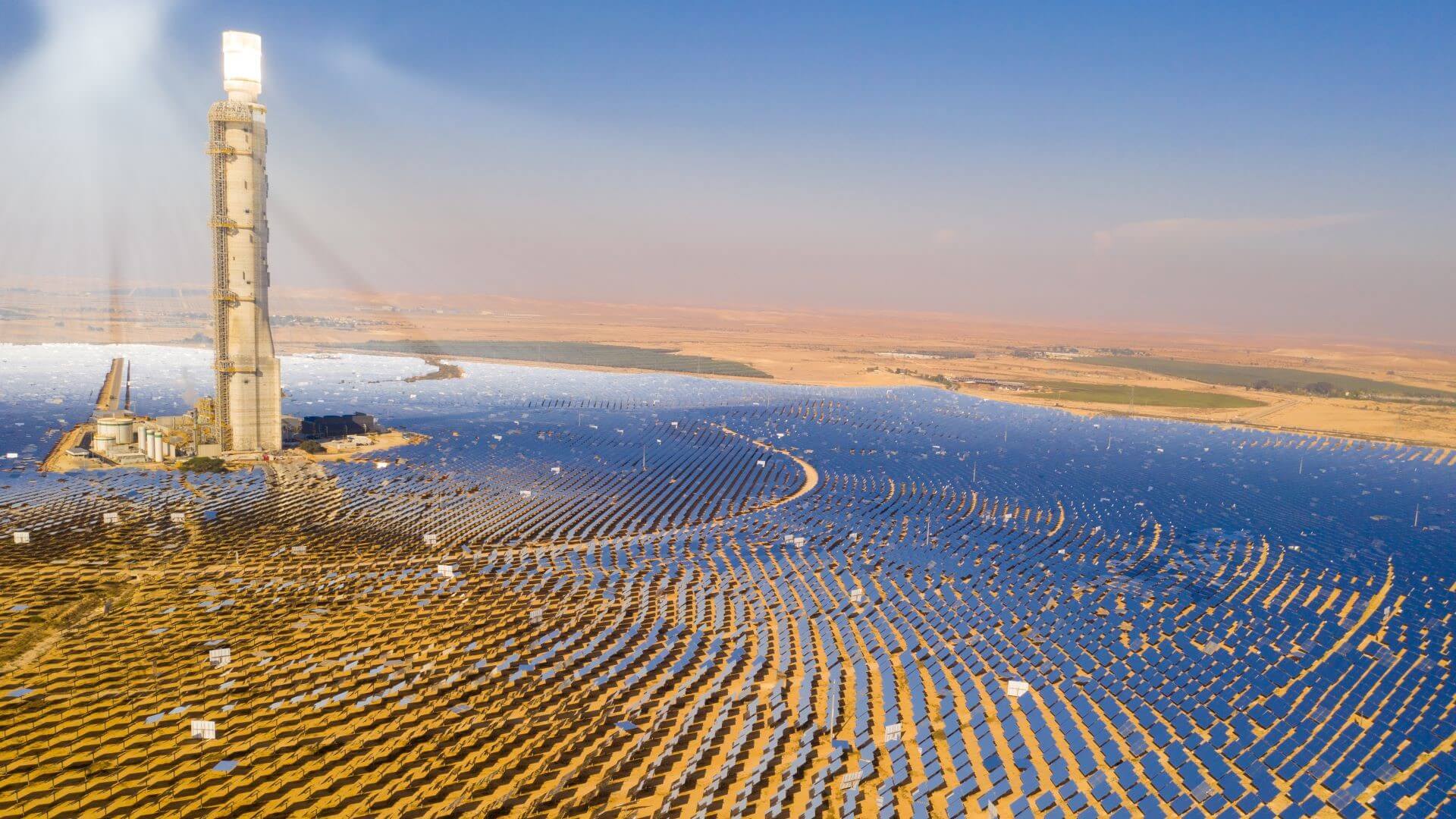 aerial view over concentracted solar power park with concentric circles of panels and central tower
