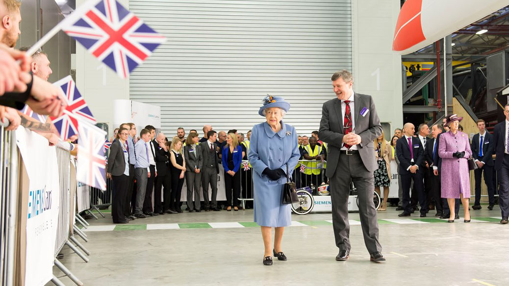 Queen visiting Siemens’ wind turbine manufacturing facility in Hull with cheeing crowds to the left and staff behind and to the right