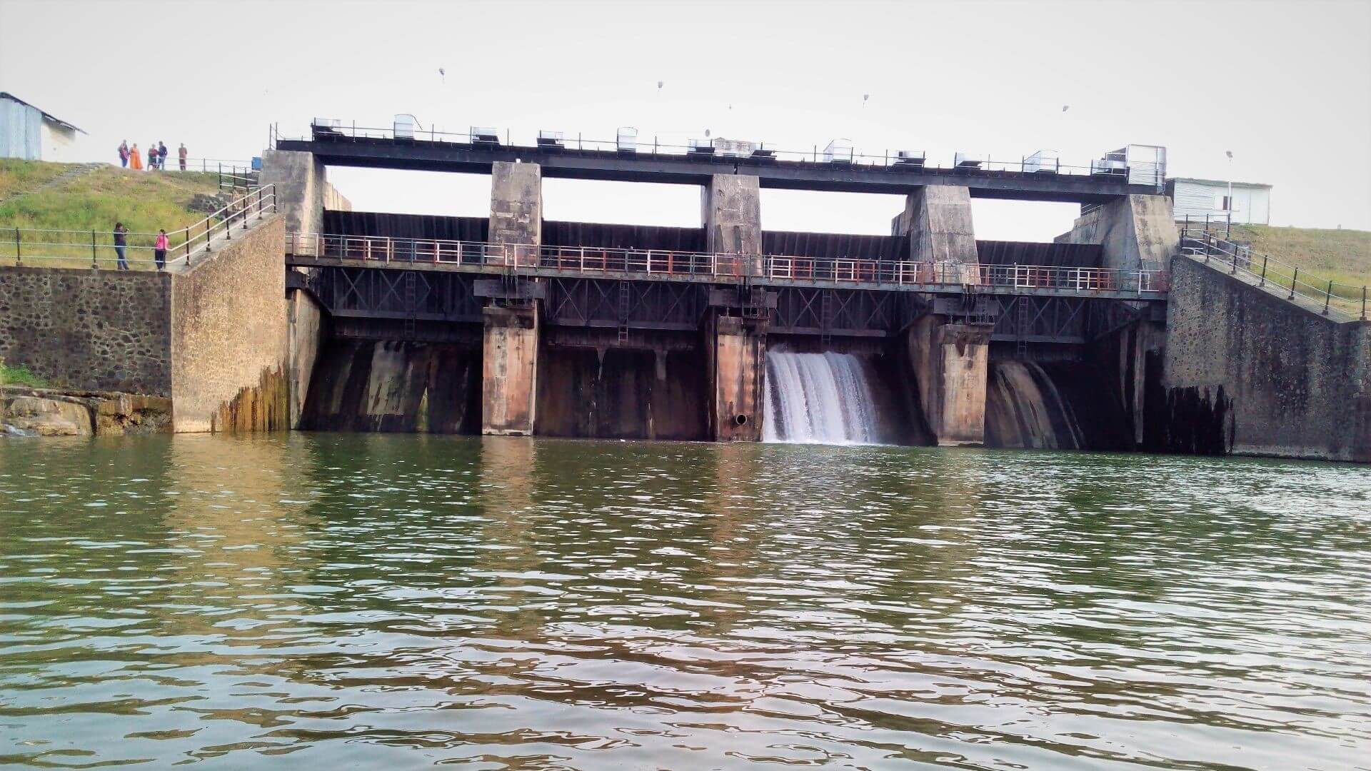 view up water to face of small hydro dam with water pouring out of an outlet