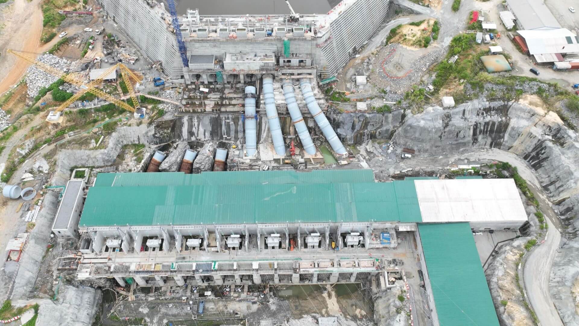 cranes constructing turbines at dam site