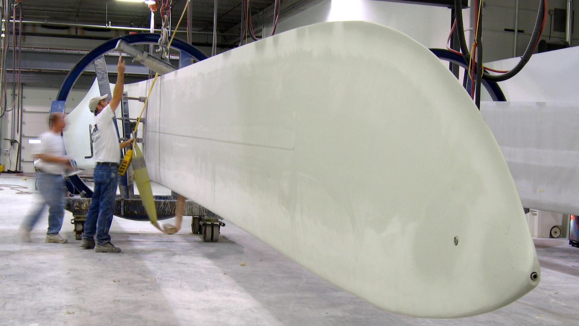 two men in a manufacturing hall, working on a wind turbine blade