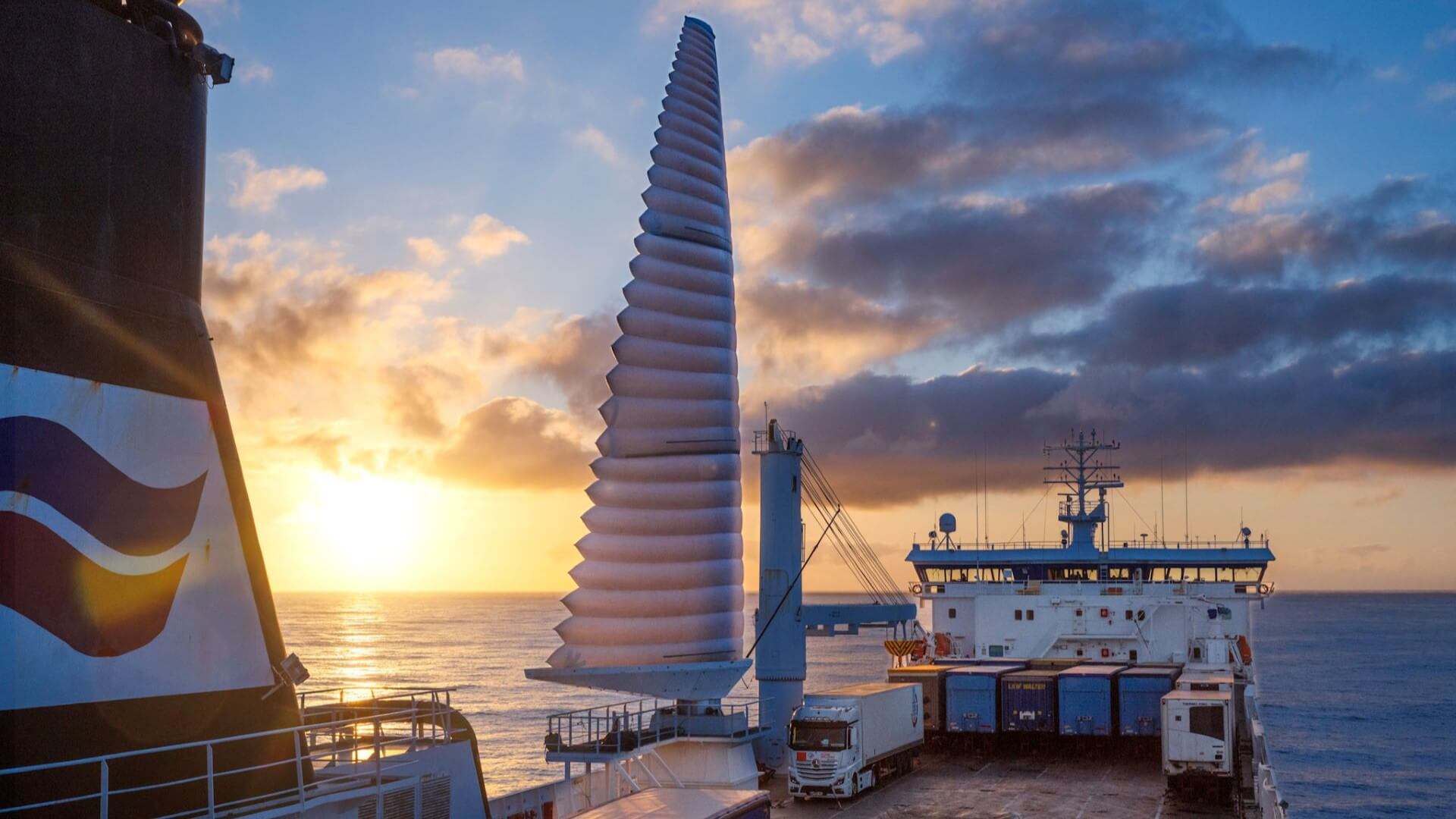 close up shot from tanker deck of triangular ridged flexible sail set against sunset sky